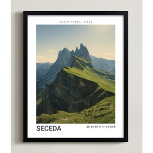 Puede incluir: Un cuadro enmarcado con una vista panorámica de Seceda, Tirol del Sur, Italia. La imagen muestra una cordillera con laderas verdes y cubiertas de hierba y picos irregulares bajo un cielo azul. La impresión incluye el nombre del lugar y las coordenadas.