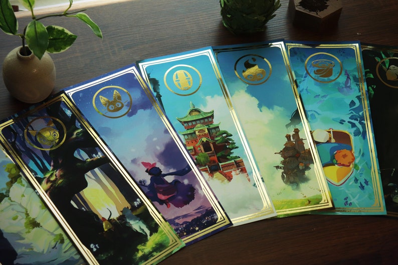 May include: Set of six gold-trimmed bookmarks featuring illustrations from Studio Ghibli films. Each bookmark has a different character or scene from a different film, including Totoro, Kiki's Delivery Service, Howl's Moving Castle, and Spirited Away.