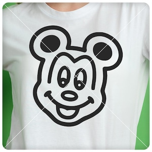 Op de afbeelding: Een wit T-shirt met een zwart-witte omtrek van Mickey Mouse's gezicht.
