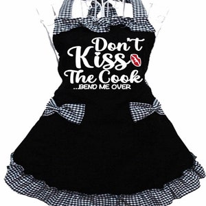 Puede incluir: Delantal a cuadros blanco y negro con un gr&aacute;fico blanco que dice "Don't Kiss The Cook...Bend Me Over" con una impresi&oacute;n de labios rojos.
