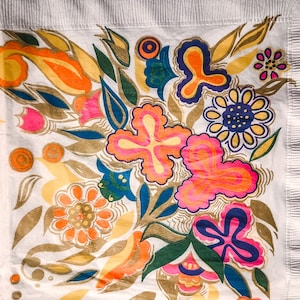 May include: A white fabric with a colorful floral pattern. The design features pink, yellow, orange, green, and blue flowers with intricate details. The background is white with a subtle texture.