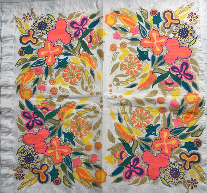 May include: A white paper napkin with a colorful floral pattern. The design features pink, orange, yellow, green, and blue flowers with a white background.