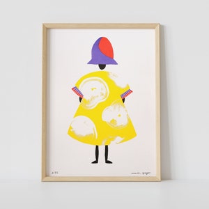 Op de afbeelding: Een ingelijste illustratie van een persoon die een gele jurk draagt met witte cirkels, een paarse hoed met een rode bovenkant en zwarte schoenen. De illustratie is gesigneerd "maura gager" en genummerd "A185".