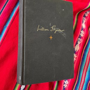 May include: A black hardcover book with the author's name "William Styron" written in gold lettering on the front cover.
