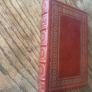 May include: A brown leather-bound book with gold accents and the title "The New World" by James A. Michener on the spine.