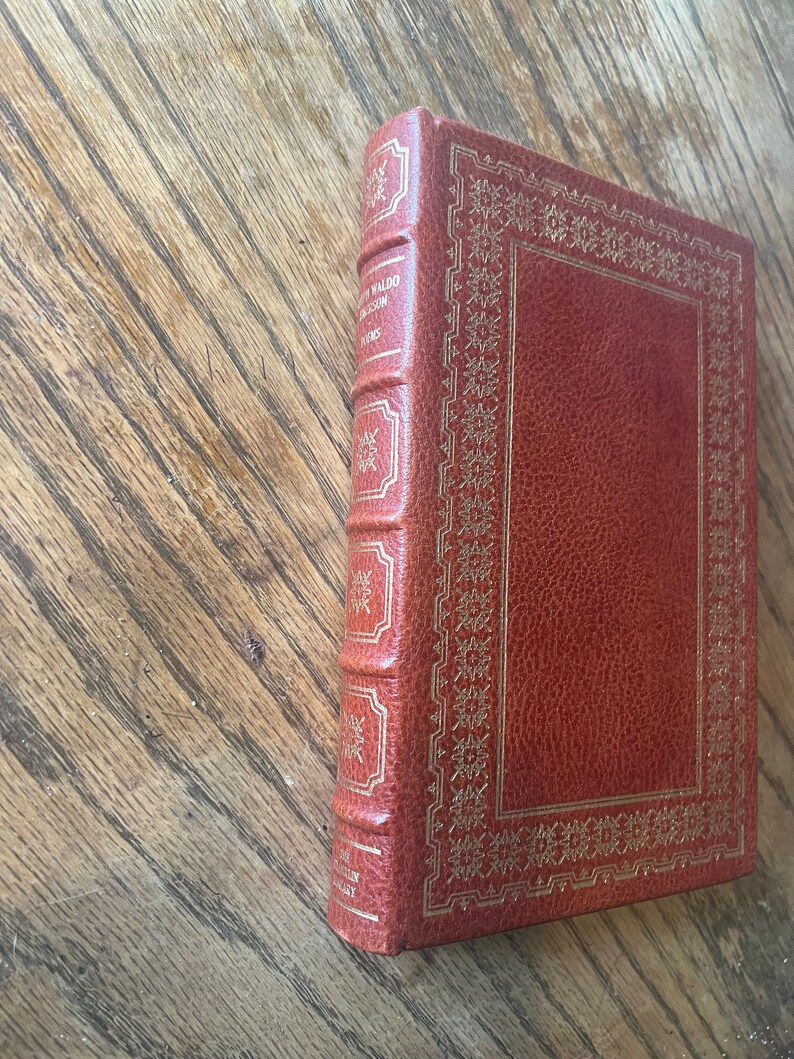 May include: A brown leather-bound book with gold accents and the title "The New World" by James A. Michener on the spine.