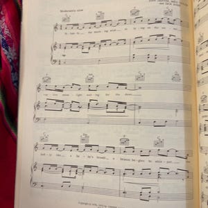 May include: Open book with sheet music for the song "Summer." The title is at the top of the page. The music is written in black ink on cream-colored paper. The page is open to a double-page spread.