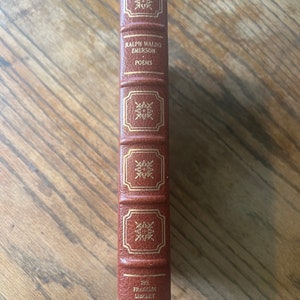 May include: A brown leather-bound book with gold lettering. The title is "Ralph Waldo Emerson Poems" and the book is part of "The Franklin Library".