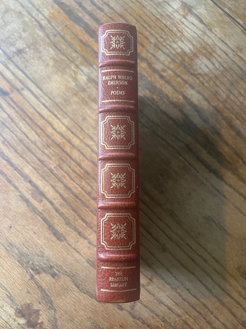 May include: A brown leather-bound book with gold lettering. The title is "Ralph Waldo Emerson Poems" and the book is part of "The Franklin Library".
