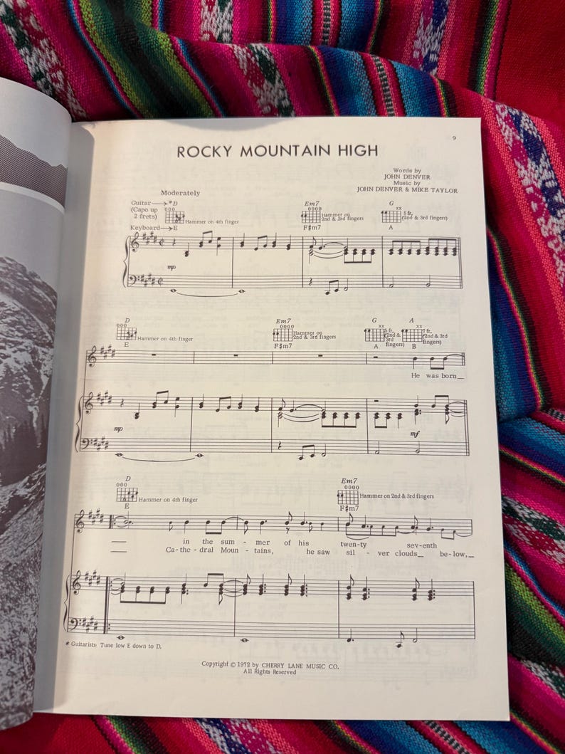 May include: Sheet music for "Rocky Mountain High" by John Denver, featuring musical notation for guitar and keyboard. The page is from a vintage songbook, with the title and composer's names at the top.