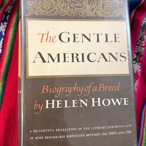 May include: A vintage hardcover book titled "The Gentle Americans: Biography of a Breed" by Helen Howe. The book cover features a decorative design in gold and brown with the title in a large, bold font.