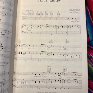 May include: Open book with sheet music for the song "Darcy Farrow." The title is at the top, with the names of the songwriters below. The music includes guitar chords and piano notes. The page is from Sparrow Music Publishing Co.