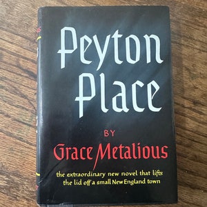 May include: A black paperback book with the title "Peyton Place" in white lettering. The author, "Grace Metalious", is written in red lettering below the title. The book cover also includes the text "the extraordinary new novel that lifts the lid off a small New England town."