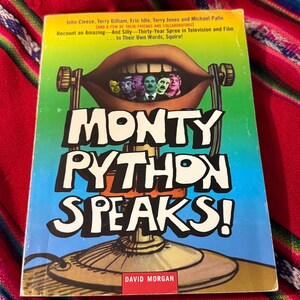 May include: A paperback book titled Monty Python Speaks! by David Morgan. The cover features a large brown mouth containing small portraits of five men, set against a green and blue background, with a microphone stand illustration at the bottom.