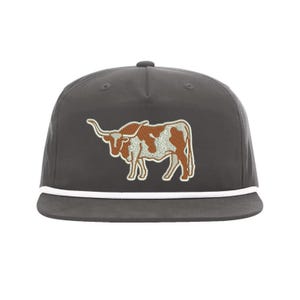 May include: A dark gray baseball cap with a white rope trim and an embroidered brown and white longhorn steer.