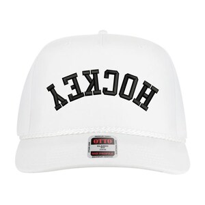 May include: White trucker hat with the word "HOCKEY" embroidered in black block letters across the front. The hat has a curved brim, a white rope detail, and a small tag on the front.