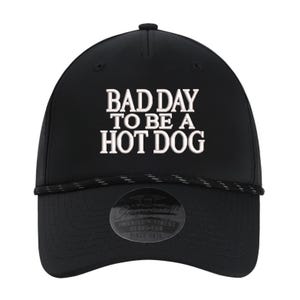 May include: Black baseball cap with the text "BAD DAY TO BE A HOT DOG" in white. The hat has a curved brim, a black rope detail, and a small patch that reads "AMERICA'S FINEST HEADWEAR SINCE 1816".