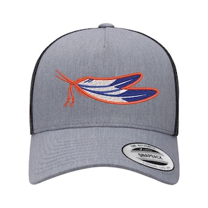 May include: Gray trucker hat with a black mesh back and a curved brim. The front features an embroidered design of a stylized insect in orange, white, and blue. The hat has a snapback closure and a white tag that reads "The Authentic Snapback".