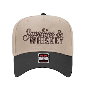 Peut inclure: Casquette de baseball beige et noire avec l'inscription "Sunshine & Whiskey" brodée en marron. La casquette a une visière incurvée et une coupe classique, avec une petite étiquette à l'avant.