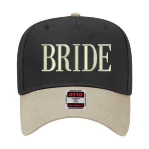 May include: A black baseball cap with the word "BRIDE" embroidered in a light beige color across the front. The brim is a light beige color. The cap has a "OTTO" tag on the brim.