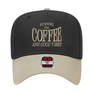 May include: A black and tan baseball cap with the text "RUNNING ON COFFEE AND GOOD VIBES" embroidered in tan thread. The cap has a curved brim and a mid-profile fit.