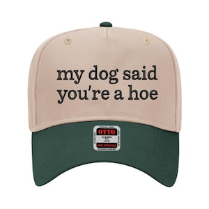 Pode incluir: Boné de beisebol bege e verde escuro com o texto preto "my dog said you're a hoe". O boné tem uma aba curva e uma pequena etiqueta Otto.