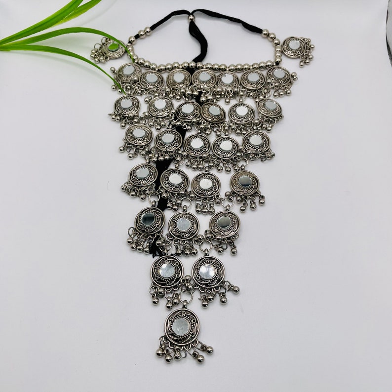 May include: Silver-toned statement necklace featuring multiple circular mirrored pendants. The necklace has a black cord and is adorned with small, dangling silver beads. The design is intricate and eye-catching, suitable for special occasions.