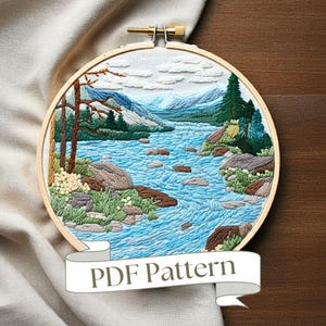 Könnte beinhalten: Stickbild in einem Holzreifen mit einem malerischen Landschaftsmotiv. Es zeigt einen gewundenen Fluss, Berge und Bäume. Der Reifen hat einen weißen Stoffhintergrund. Die Stickerei ist in Blautönen, Grün, Braun und Weiß gehalten. Unter dem Reifen befindet sich ein Banner mit dem Text "PDF Pattern".