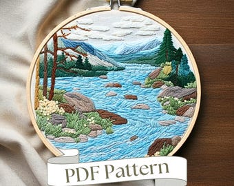 May include: Embroidered hoop art featuring a scenic landscape with a winding river, mountains, and trees. The hoop is made of wood and has a white fabric background. The embroidery is done in shades of blue, green, brown, and white. The text "PDF Pattern" is displayed on a banner below the hoop.
