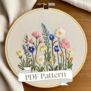 Könnte beinhalten: Stickerei mit Blumenmotiv in einem Holzreifen mit verschiedenen bunten Blumen, darunter rosa, blaue, gelbe und weiße. Der Reifen ist aus Holz und hat eine natürliche Oberfläche. Der Text "PDF Pattern" ist auf einem Banner unter dem Reifen zu sehen.