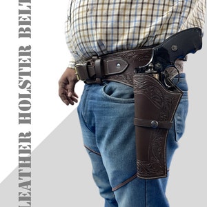 May include: A brown leather holster with intricate floral designs, worn on a brown leather belt with a silver buckle. The holster is designed to hold a handgun, which is partially visible in the image.