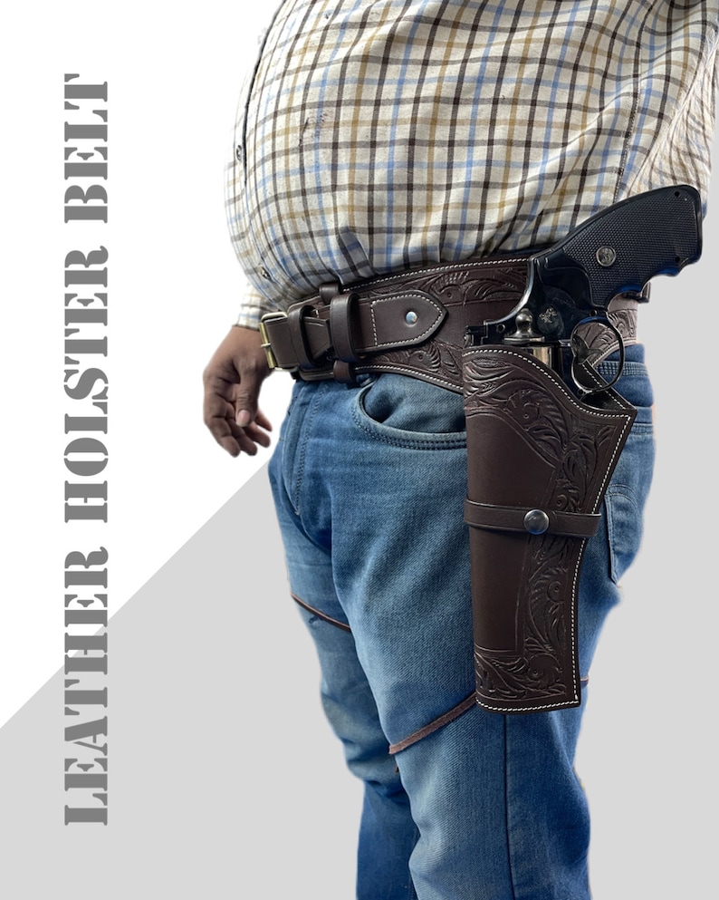 May include: A brown leather holster with intricate floral designs, worn on a brown leather belt with a silver buckle. The holster is designed to hold a handgun, which is partially visible in the image.