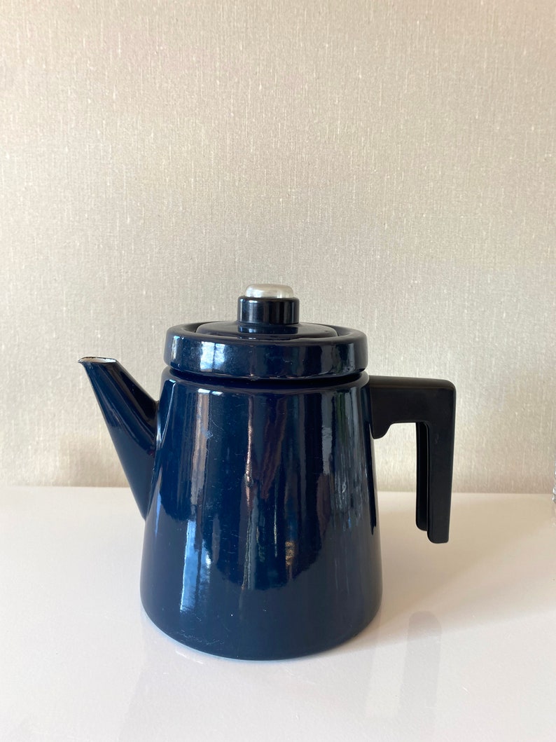 May include: A dark blue enamel coffee pot with a black handle and a silver knob on the lid.