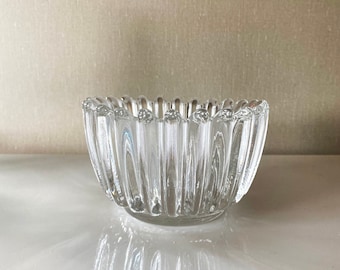 May include: A clear glass bowl with a fluted design. The bowl is empty and has a reflective surface.