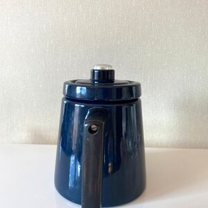 May include: A dark blue enamel teapot with a black handle and a silver knob on the lid.