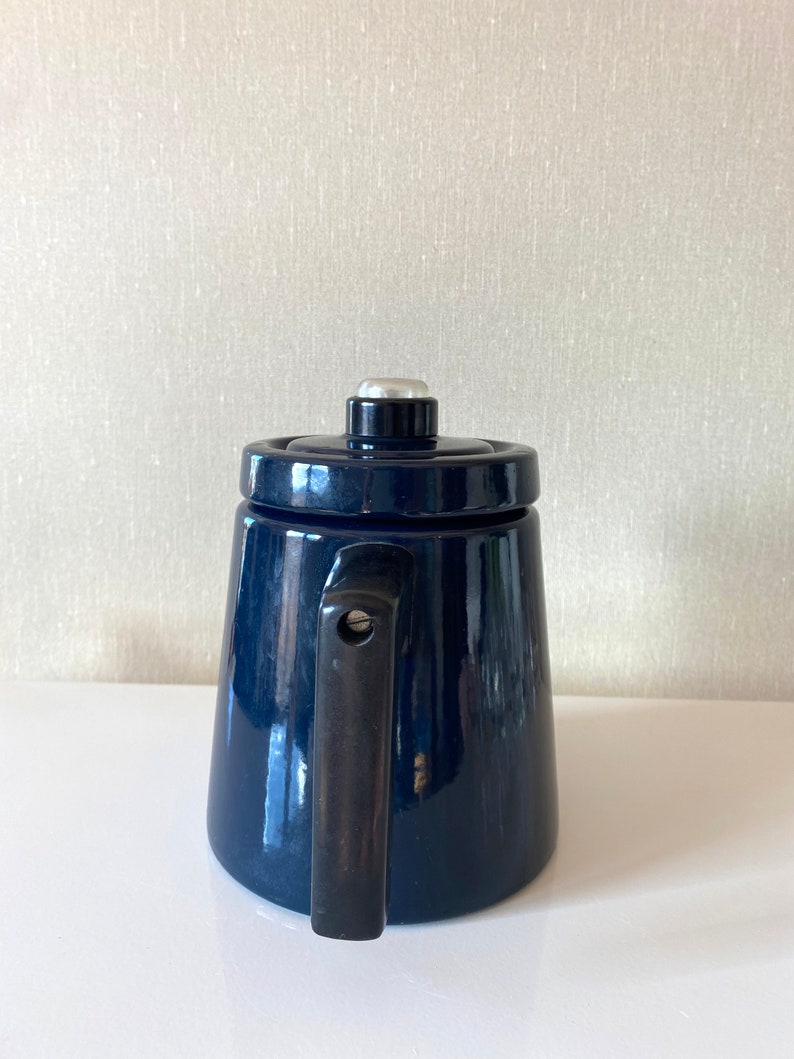 May include: A dark blue enamel teapot with a black handle and a silver knob on the lid.
