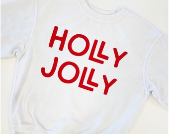 Puede incluir: Sudadera blanca con texto rojo que dice "Holly Jolly" en la parte delantera.