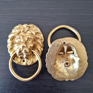 Può includere: Una tazza di ceramica bianca con manico nero e la scritta "But First, Coffee" in grassetto nero. La tazza è appoggiata su una superficie di legno. La tazza è alta circa 10 cm.