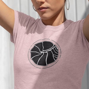May include: A woman wearing a pink t-shirt with a black and white graphic design of a spiral. The graphic is centered on the shirt.
