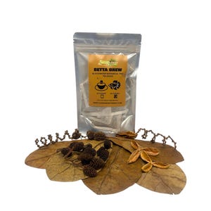 May include: A clear, sealed bag of "Betta Brew" tea bags. The label is orange and black, with the text "Blackwater Botanical Tint Tea Bags." The tea bags are displayed on a decorative leaf arrangement with small pinecones and dried leaves.