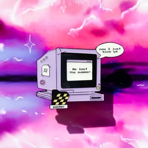 Könnte beinhalten: Eine lila und schwarze Emaille-Anstecknadel mit einem Retro-Computer, auf dessen Bildschirm der Text "We lost the summer" zu sehen ist, und einer Sprechblase mit dem Text "now I just miss ya". Die Anstecknadel hat unten ein Schachbrettmuster und darunter steht das Wort "winter".