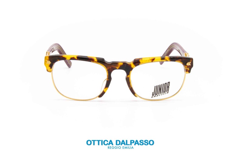 May include: Tortoise shell eyeglasses with gold metal frames and clear lenses. The brand name "JUNIOR" is printed on the right lens.
