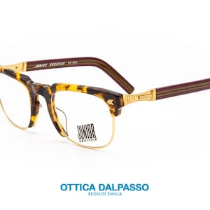 May include: Tortoise shell eyeglasses with gold metal accents and burgundy temples. The brand name "Junior Gauthier" is printed on the temple.