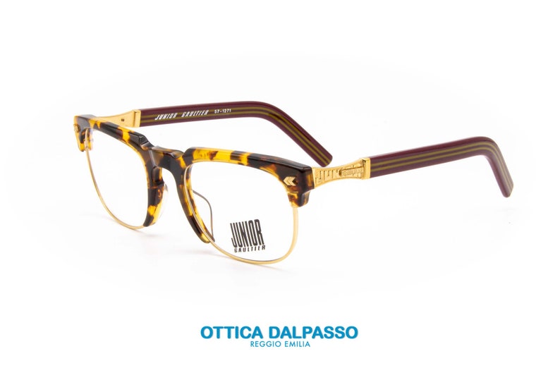May include: Tortoise shell eyeglasses with gold metal accents and burgundy temples. The brand name "Junior Gauthier" is printed on the temple.