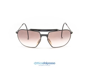 May include: Black aviator sunglasses with a metal frame and brown gradient lenses. The sunglasses have a unique design with a metal bar connecting the two lenses.