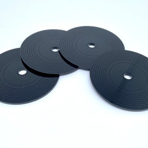 K&ouml;nnte beinhalten: Vier schwarze Untersetzer in Form von Schallplatten mit konzentrischen Kreisen und einem kleinen Loch in der Mitte.