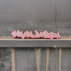 a graffiti style tag in red and black that says harley davidson