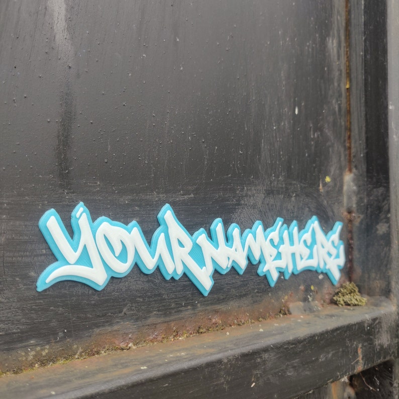 a 3d printed graffiti tag that says 'your name here' in white with a blue background