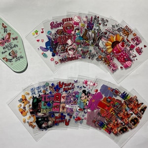 May include: Assortment of colorful clear plastic sheets with various cartoon and graphic designs. The designs include butterflies, flowers, hearts, stars, and characters like Mickey Mouse, Hello Kitty, and a mermaid. The sheets are perfect for crafting and scrapbooking.