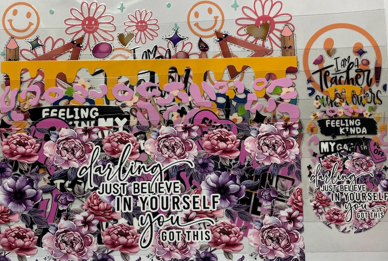 Pu&ograve; includere: Una collezione di adesivi a tema floreale con vari disegni e testo. Gli adesivi presentano fiori rosa e viola, faccine sorridenti, matite e le frasi "darling", "Just Believe in Yourself" e "I am a Teacher, Sunflower."